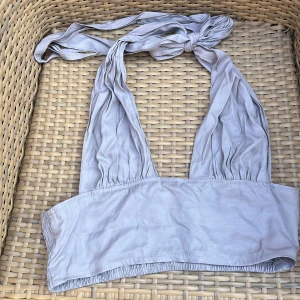 Ljuslila halterneck tubtopp med knyt - Supersöt ljuslila tubtopp med halterneck och breda knytband i nacken. Toppen har rynkade detaljer framtill och smockad baksida för extra komfort. Perfekt till varma dagar och snygg att styla med höga jeans eller kjol.