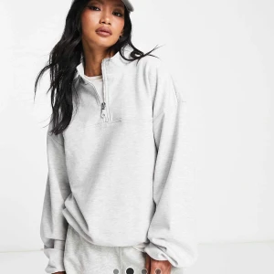 Oversized ljusgrå half zip sweatshirt - Oversized ljusgrå sweatshirt med half zip-dragkedja och hög krage. Tröjan har långa ärmar och en avslappnad passform.