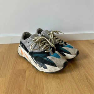 Yeezy Wave Runner  - Säljer ett par Adidas Yeezy Wave Runner 700 med chunky sula och cool färgkombo av grått, svart, blått och orange. Skorna har mesh och mockadetaljer, snörning och retrovibbar. Perfekta för dig som gillar streetwear och vill sticka ut. Välanvända och slitna men ändå snygga. 
