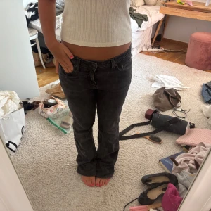 Svarta bootcut jeans med låg midja - Säljer ett par svarta jeans med lätt tvättad look och bootcut-ben. De har låg midja och klassisk femficksmodell. Perfekta om du gillar en avslappnad men ändå snygg stil. Materialet är jeans och passformen är normal.