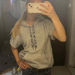 Kortärmad hoodie  - Kortärmad hoodie med zebra mönstrade band. Jag har sytt om en vanlig hoodie från hm (sytt in midjan, sytt om armarna). Och snörerna är även köpte reparat. Säljer då den tyvärr inte används längre. Om de önskas bild på sömar osv kan jag absolut skicka det!!