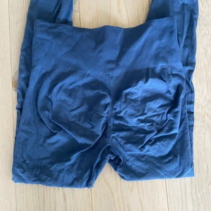 Blå seamless leggings med hög midja - Säljer ett par mörkblå seamless leggings med hög midja. De är stretchiga och har en tight passform som sitter snyggt och bekvämt. Materialet är mjukt och följsamt, perfekt för träning eller chill. Diskret mönster längs benen för extra stilpoäng. Tightsen har scrunch där bak som framhäver baksidan perfekt💙xs/s