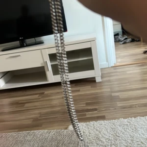 Kedjehalsband i silverfärg - Snyggt halsband med klassisk kedjedesign i silverfärg. Länkarna är platta och breda vilket ger ett stilrent och modernt intryck. Perfekt för dig som vill ha en enkel men ändå cool detalj till din outfit. Låsningen är smidig och lätt att använda.