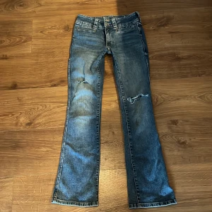 Bootcut jeans med hål - Blåa bootcut jeans med hål som jag gjort själv, flap pockets/knappar där bak. Går även att justera i midjan. Liten defekt (bild 4) ☺️
