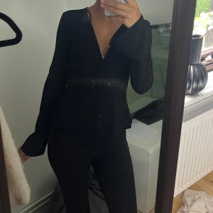 Svart omlottopp med spets från Gina Tricot - Supersnygg svart omlottopp från Gina Tricot med lång ärm och v-ringning. spets i midjan, Aldrig använd utan endast testad💓