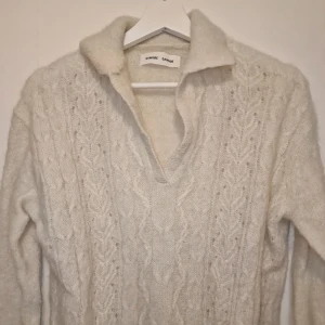 Stickad vit tröja från Samsøe Samsøe - Mysig stickad tröja från Samsøe Samsøe i mjuk vit alpackaull. Tröjan har ett snyggt kabelstickat mönster framtill, klassisk krage och v-ringad hals. XS men passar mig som har S. Använd vid max 5 tillfällen och kostade under 3000 kr vid inköp. 