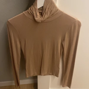 Beige polotröja från Bik Bok XS - Snygg beige polotröja från Bik Bok i storlek XS. Tröjan har lång ärm och en hög krage som ger en chill och stilren vibe. Mjuk och tunn i materialet, perfekt att matcha med jeans eller kjol. Enkel design utan mönster eller detaljer.