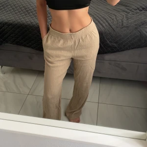 Beige linnebyxor med loose fit - Beige linnebyxor från H&M med skön loose passform och elastisk midja. Byxorna har raka ben och är tillverkade i ett lätt och luftigt linnematerial, perfekta för varma dagar. 