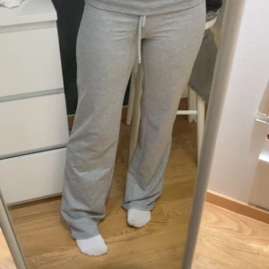 Grå mjukisbyxor med snörning - Säljer ett par grå mjukisbyxor med snörning i midjan. Byxorna har en loose passform och raka ben, perfekta för chill dagar hemma eller när du vill vara extra bekväm. Materialet är mjukt och stretchigt bomullstyg som känns skönt mot huden. ! Liiiite noppriga !