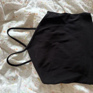 Svart ribbad linnetopp från Zara - Svart ribbad linnetopp från Zara med smala axelband och rak halsringning. Toppen är croppad och har en stilren, enkel design som är lätt att matcha med olika outfits. Perfekt för dig som gillar minimalistisk stil och vill ha en topp som funkar året runt.