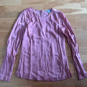 Ljusrosa blus från H&M - Säljer en ljusrosa blus från H&M i storlek 34. Blusen har rund halsringning, lång ärm och en diskret dragkedja bak. Materialet är mjukt och lätt, tillverkat av 56% viskos och 44% polyester. Färger på blusen är på den fjärde bilden, inte de tre första