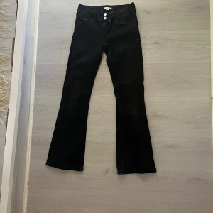Svarta bootcut jeans från Gina Tricot - Snygga svarta jeans från Gina Tricot i storlek 158. Modellen har bootcut-ben, klassiska fem fickor och dubbla knappar fram. Jeansen är tillverkade i ett stretchigt bomullsmaterial som sitter skönt och ger en cool siluett. 
