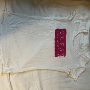 Vit T-shirt från Guess - Vit/rosa T-shirt från guess, står ingen storlek men tror det är XS