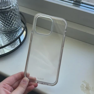 Genomskinligt mobilskal från Holdit  - Säljer nu ett genomskinligt mobilskal med vita sidor från Holdit till 14 PRO Max. Skalet är använt ett fåtalet gånger och har små tecken på användning. Nypris är 249kr