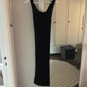 Svart långklänning från Lindex - Säljer en svart långklänning från Lindex i storlek S. Klänningen har en stilren, ärmlös design med rundad halsringning och ribbad struktur i materialet. Perfekt för dig som gillar minimalistisk och tidlös stil.