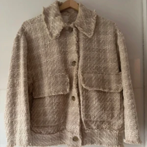 Beige jacka från H&M i S - Säljer en beige jacka från H&M i storlek S. Jackan har ett grovt, stickat rutmönster, stora fickor framtill och knappar längs hela framsidan. Den har en klassisk krage och långärmade ärmar. Perfekt för dig som gillar chill och trendig stil. Stor i storleken och passar M också. Hade på mig 2 gånger. Bomull 67%