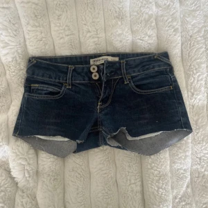 Mörkblå jeansshorts - Snygga mörkblå jeansshorts från Trf denimrules med rå kant och dubbla knappar framtill. Klassisk femficksdesign och kontrastsömmar ger en cool vibe. Perfekta för varma dagar och passar till allt. avklippta skinny jeans