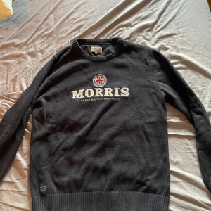 Marinblå stickad tröja från Morris XL - Marinblå stickad tröja från Morris i storlek XL med broderad logga på bröstet. Tröjan har rund hals, ribbade muddar och är långärmad. Tröjan är liten i storlek, passar L. Använd och tvättad endast en gång.