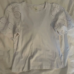 Vit blus från H&M - Superfin vit blus från H&M med fint mönster i armarna. 