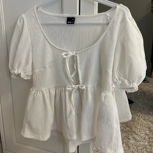 Jättesöt Vit blus med puffärm från Gina!🫶🏻 - Supersöt vit blus från Gina Tricot i storlek XXS. Blusen har puffiga korta ärmar, två knytningar framtill och en lätt rynkad, helt oanvänd, säljer för att den är för stor på mig🥰