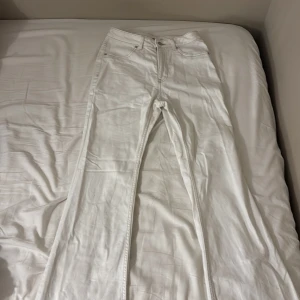Vita bootcut jeans med hög midja - Säljer ett par vita jeans med bootcut passform och hög midja. Klassisk femficksmodell med knapp och dragkedja framtill. Perfekta för dig som gillar en clean och fräsch look. Passar till sneakers eller boots för en cool vibe.