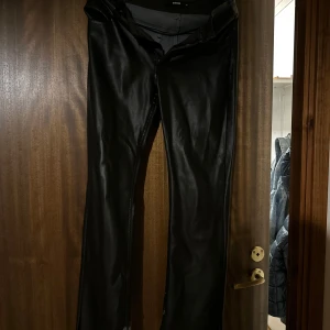 Svarta bootcut byxor i skinnimitation - Säljer ett par svarta byxor i skinnbyxor men de har fått några små fläckar som knappt märks av