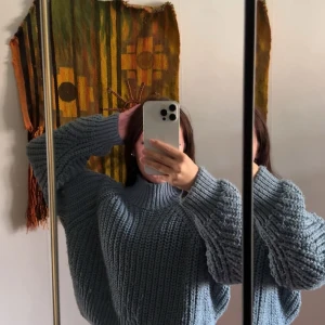 Blå stickad oversized tröja - Supermysig blå stickad tröja med oversized passform och höga muddar. Tröjan har en hög krage och grovstickat mönster som ger en cool och avslappnad vibe. Perfekt för lager-på-lager och chill dagar.