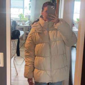 Beige pufferjacka från Vero Moda (PRIS KAN DISKUTERAS) - Säljer en beige pufferjacka från Vero Moda med huva och dragkedja framtill. Jackan har en oversized passform och är quiltad med breda kanaler. Perfekt för kalla dagar och har långa ärmar samt snygga detaljer vid huvan. Storlek är xs men kan definitivt passa som en M och kanske möjligt en L . Har blivit använd 1-3 gånger men itne blivit använd för att storleken varit för stor🥰😊