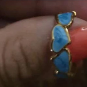 Guldring med blå hjärtan - Unik guldfärgad ring med flera blå hjärtformade detaljer runt hela ringen. Perfekt för dig som vill ha något färgglatt och annorlunda på fingret. Hjärtana har en cool, oregelbunden form som ger ringen en lekfull vibe.