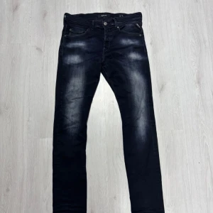 Mörkblå Replay jeans, storlek 33/34 - Snygga mörkblå jeans från Replay i klassisk femficksmodell. Jeansen har diskreta slitningar framtill och bakfickor med broderad detalj. Modellen är rak och passar perfekt till en avslappnad stil. Tillverkade i bomull med lite stretch för extra komfort. Dock ett litet hål i längst bak i skrevet!