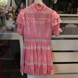 Rosa kortklänning från By Malina - Supersöt rosa klänning från By Malina med volanger och spetsdetaljer, knappt använd 💕nypris 2600 kr 