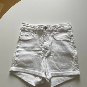 Vita jeansshorts från Gina Tricot - Snygga vita jeansshorts från Gina Tricot, modell Molly. Klassisk femficksdesign, uppvikta benslut och knapp- samt dragkedjestängning. Perfekta för varma dagar och lätta att matcha med allt.
