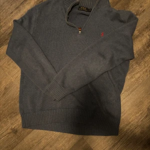 Blå ralph polo half zip  - Blå stickad tröja från Polo Ralph Lauren med half zip och hög krage. Klassisk röd logga broderad på bröstet. Långärmad modell med ribbade muddar och nederkant. Perfekt för lager-på-lager och snygg till jeans. Pris kan diskuteras. 