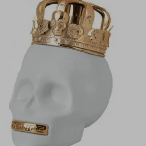Parfymflaska i form av dödskalle - Unik parfymflaska från Police i form av en vit dödskalle med en detaljerad guldfärgad krona som lock. Flaskan har även en guldfärgad detalj vid munnen. Perfekt för dig som gillar edgy och cool design.