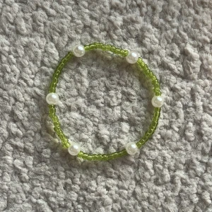 Armband - Fint handgjort pärlband med små olivgröna pärlor och lite större vita pärlor. Armbandet är nosize men är i tjej storlek så passar dig om du har handledsmått 15-18 cm