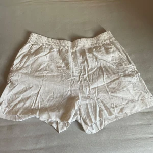 Vita linne-shorts med resårmidja - Snygga och luftiga vita shorts i linne med elastisk midja och sidfickor. Perfekta för varma dagar när du vill ha en chill och stilren look. Passformen är relaxed och materialet känns svalt mot huden.