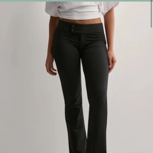 Svarta bootcut byxor med låg midja - Snygga svarta byxor med bootcut-snitt och låg midja. Byxorna ser exakt likadana ut som bilden fast utan knapparna