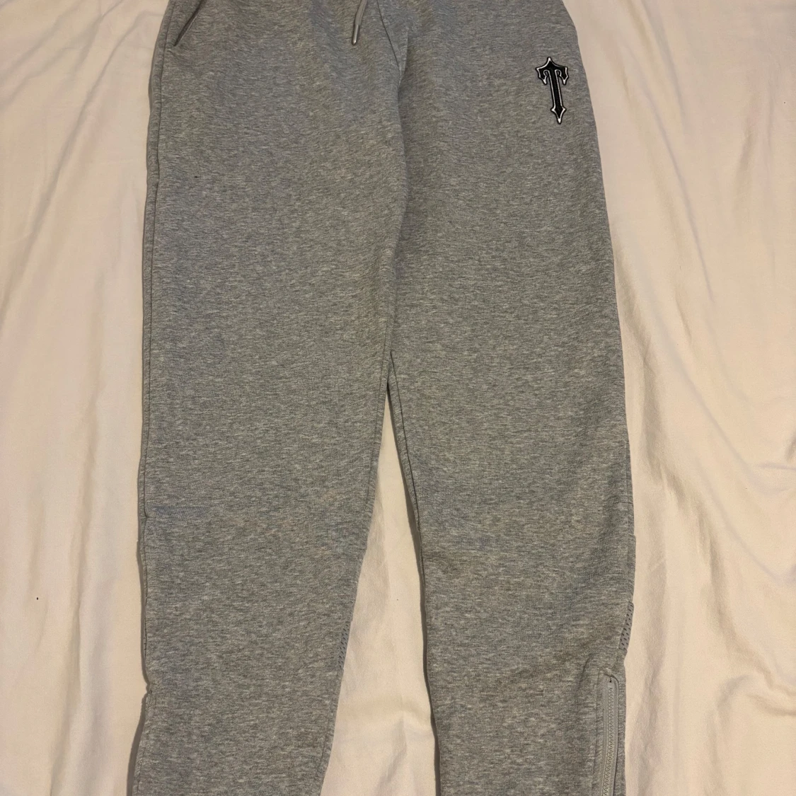 Grå trapstar byxa med en svart T loga på låret
