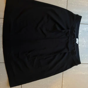 Svart kortkjol från Filippa K - Enkel och stilren svart kortkjol från Filippa K. Kjolen har en rak passform och bred linning i midjan. Perfekt att matcha med en cool t-shirt eller stickad tröja. Klassisk design som funkar till många olika looks. Mammas kjol som inte kommer till användning längre:)