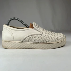  Bottega Veneta skor - Snygga vita slip-on sneakers från Bottega Veneta med flätad skinnstruktur. Skorna har en platt sula och rund tå, vilket ger en clean och stilren look. Perfekta för dig som gillar exklusiva detaljer och italiensk design.