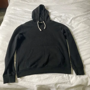 Svart hoodie från Pier One, storlek M - Svart hoodie från Pier One i storlek M. Klassisk modell med huva och vita snören, stor magficka framtill och ribbade muddar vid ärmslut och nederkant. Perfekt för chill dagar och enkel att matcha med jeans eller joggers.