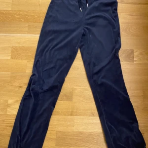 Mörkblå mjukisbyxor från Gina Tricot - Säljer ett par mörkblå mjukisbyxor från Gina Tricot med snörning i midjan och två bakfickor. Byxorna har en loose passform och är gjorda i mjukt, fleeceliknande material som är superbekvämt. Perfekta för chill eller häng med kompisar.