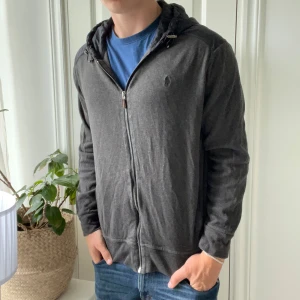 Ralph Lauren cardigan  - Riktigt skön cardigan. Lite urtvättad men inga större defekter. Passar bra på modellen som är 180,75 kg. Den sitter mer slim fit än den exakt likadana som jag också har uppe. Estate rib vilket är ett najs material. Storlek L. Färg är kaki/ grå