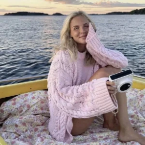 Ljusrosa stickad tröja med flätmönster - Supermysig ljusrosa stickad tröja med breda ärmar och snyggt flätmönster längs sidorna och ärmarna. Tröjan har en rund halsringning och är oversized för en chill vibe. Perfekt att slänga på sig när det är lite kyligt ute.