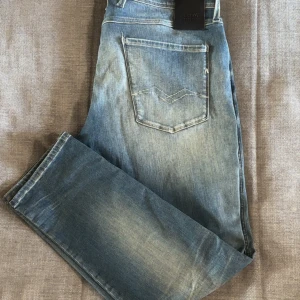 Replay Anbass Hyperflex jeans blå - Säljer ett par Replay Anbass Hyperflex jeans i ljusblå tvätt med snygga slitningar. Klassisk femficksmodell med raka ben och normal passform. Jeansen har stretchigt material som gör dem riktigt sköna att bära. Perfekta för dig som gillar en avslappnad stil. Väldigt fetta knappt använda jeansen är köpa i butik, bara att höra av sig vid frågor osv 😁