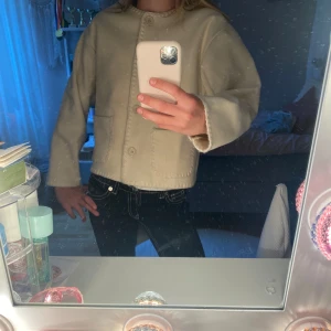 Beige cardigan jacka från RYVLS - Superfin beige cardigan jacka från RYLS med snygga dekorativa sömmar längs kanterna, stora knappar framtill och två praktiska fickor🥰.