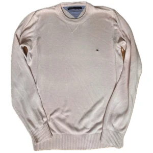 Stickad tröja Tommy Hilfiger - Säljer en stilren ljusrosa stickad tröja från Tommy Hilfiger. Tröjan har rund halsringning, diskret logga på bröstet och är tillverkad i 100% bomull. Perfekt för lager-på-lager och passar till många olika outfits.