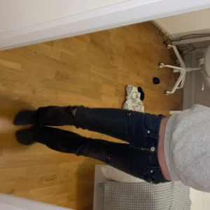 Svarta jeans med slitningar - Snygga svarta jeans med slitningar på knäna och en cool, sliten look. De har en klassisk femficksdesign och knappar i midjan. Perfekta för en avslappnad stil.