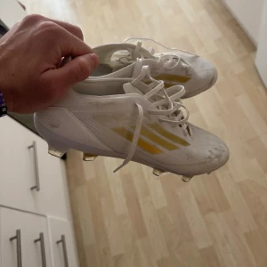 Fotbollsskor från Adidas - Vita fotbollsskor från Adidas. Använda ett par gånger men säljs nu för att de inte passade. Liten defekt finns, vänster fram (kolla bild).  Köpta för 1800kr på Unisport.