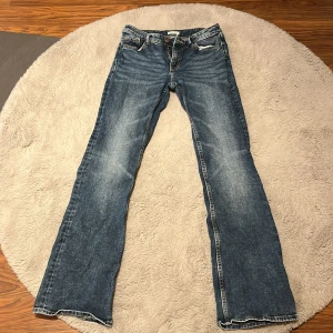 Blå lågmidjade bootcut jeans  - Säljer ett par klassiska blå lågmidjade bootcut jeans från Lindex med en snygg tvätt. De har en låg midja och fem fickor. Perfekta för en avslappnad stil.